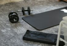 하루 20분 운동의 기적: 건강의 비결 a pair of dumbbells and a black mat on the floor