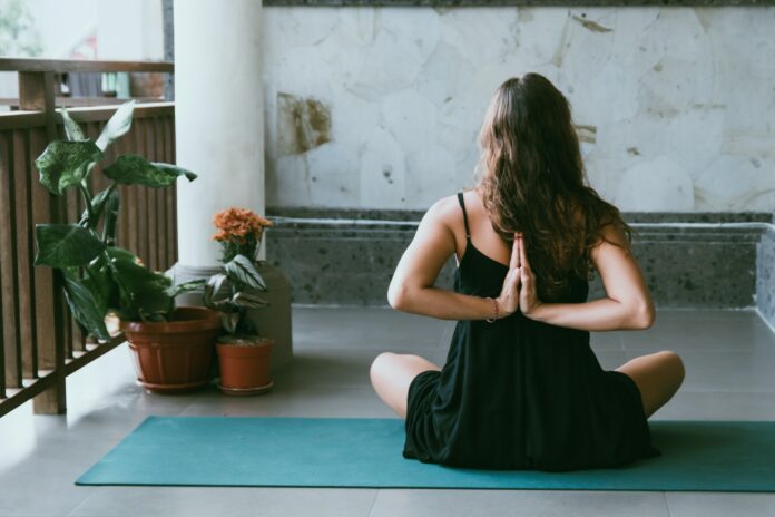 Photo by Avrielle Suleiman woman wearing black shirt sitting on green yoga mat